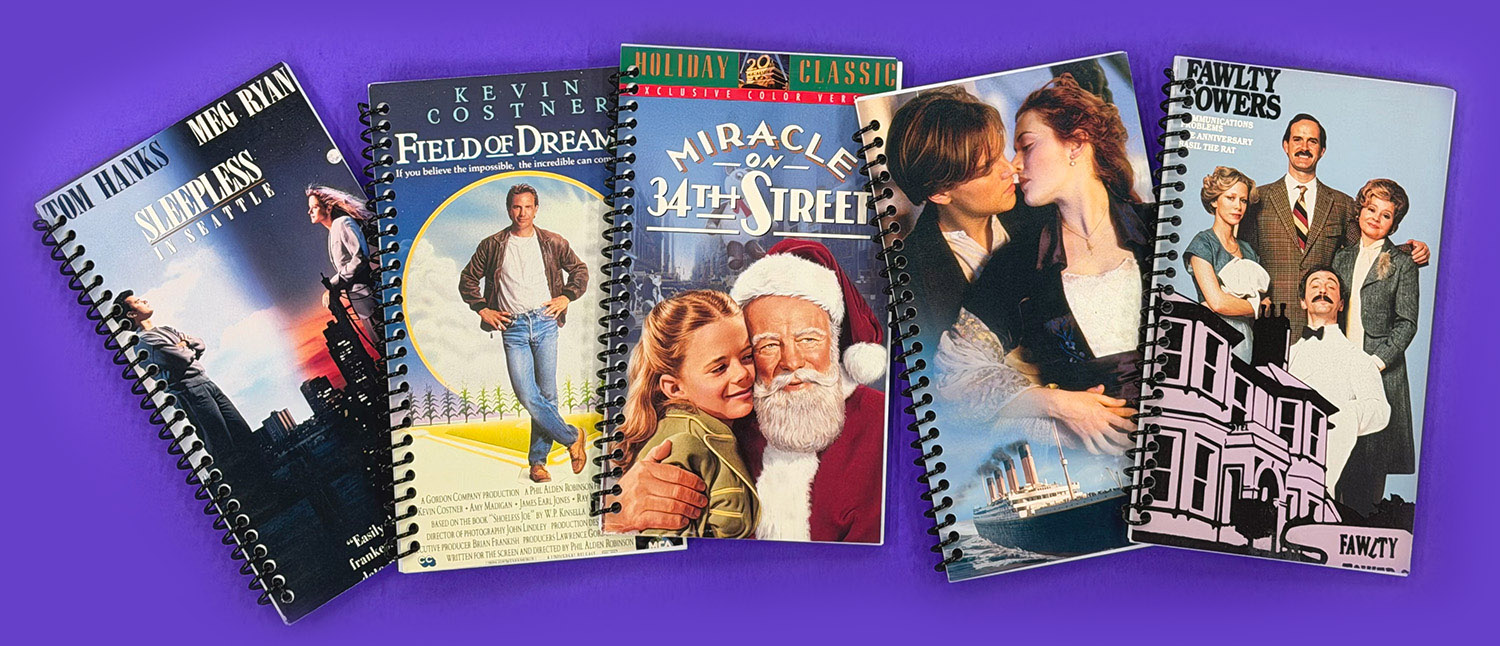 Spiral notebooks made from VHS covers of Sleepless in Seattle, Field of Dreams, Miracle on 34th Street, Titanic and Fawlty Towers.